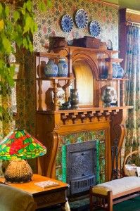 a living room filled with furniture and a fire place in front of a wallpapered wall