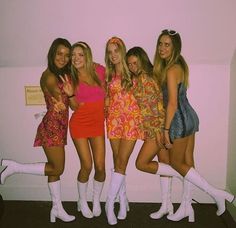 four beautiful young women standing next to each other in short dresses and knee high boots