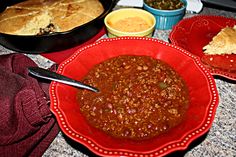 chili in a red bowl next to other dishes