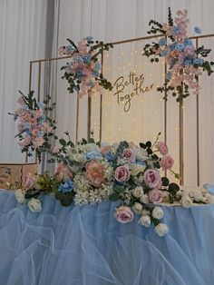 a table topped with flowers and greenery next to a sign that says better together