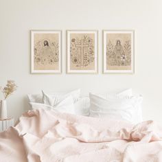 two framed pictures hang above a bed with pink sheets and blankets on top of it