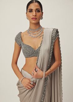 This exquisite Grey Crystal and Sequin Hand Embroidered Satin Saree Set is the perfect fusion of traditional elegance and modern sophistication. Made from luxurious satin and georgette, the grey saree features intricate hand embroidery with shimmering sequins and tonal crystal embellishments along the borders, offering a subtle yet opulent look. Paired with a cap-sleeved blouse adorned with sparkling crystal accents, jewelled design that adds a chic, contemporary twist. Ideal for Mehndi, Sangeet ceremonies, or as a statement saree at reception. Composition : Saree - Satin and Blouse - Georgette Care: Dry Clean Only and Vacuum Storage This product can be customized for sleeves, blouse length and neckline Delivery : 6-8 weeks as the product is hand crafted. Check Size Guide or choose MySize Grey Satin Saree, Satin Sari, Saree Satin, Sequin Saree, Grey Saree, Crystal Embroidery, Vacuum Storage, Cap Sleeves Blouse, Indian Wedding Wear