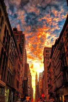 a city street filled with tall buildings under a colorful sky at sunset or sunrise in new york city