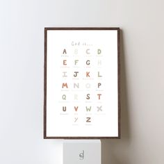 a poster with the alphabet displayed on top of a white shelf next to a wall