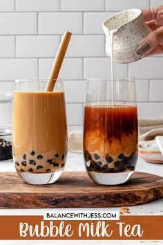 two glasses filled with bubble milk tea on top of a cutting board