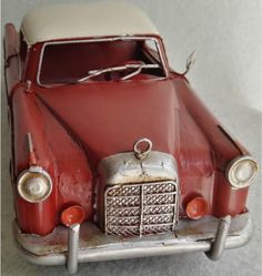 an old red toy car sitting on top of a table