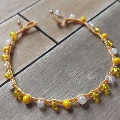 a yellow and white beaded bracelet sitting on top of a wooden floor