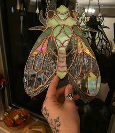 a hand holding a stained glass bee ornament in it's right hand