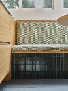 a wooden bench sitting next to a window in a room with tiled floors and walls