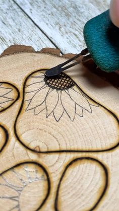 a person using a pair of scissors to cut a piece of wood with flower designs on it