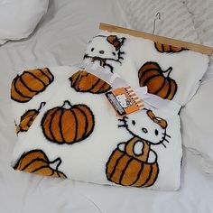 an orange and white hello kitty blanket on top of a bed next to a tag