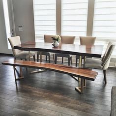 a wooden table with four chairs and a bench in front of it on a hard wood floor