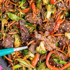 beef and broccoli stir fry in a wok with sesame seeds on top