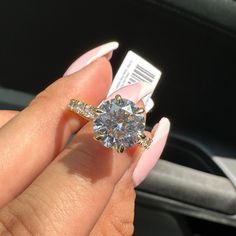 a woman's hand holding an engagement ring with a diamond on it, in front of a car