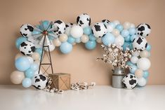 the balloon arch is decorated with blue, white and black balloons that look like cows