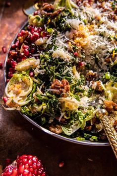 a bowl filled with lots of food on top of a wooden table next to pomegranates