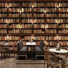 a library filled with lots of books next to tables and chairs on top of hard wood flooring