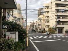 an empty city street with buildings on both sides and people riding bikes in the middle