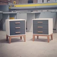 two grey and white dressers sitting next to each other in front of a machine