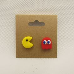 two pacman and moon shaped buttons sitting on top of a brown package with white background