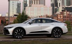 a white car parked in front of a city skyline