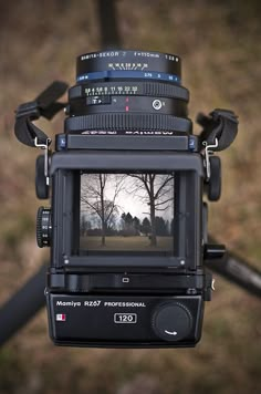 a camera with a lens attached to it's body and some trees in the background