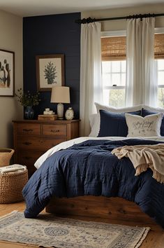 a bedroom with blue and white bedding, two windows, rugs on the floor