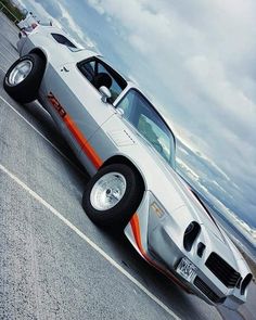 a silver and orange car parked on the side of a road next to the ocean