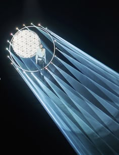 a man standing on top of a stage in front of a giant light ball with strings