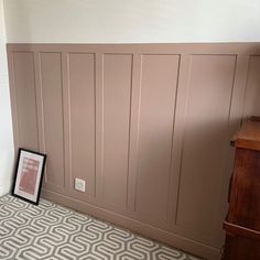 an empty room with wood paneling on the wall and a framed photograph in front of it