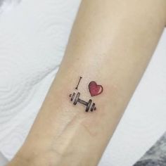 a woman's arm with a tattoo on it that has a heart and a barbell