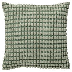 a green pillow with white dots on the front and back, sitting on a white surface