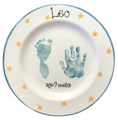 a white plate with blue handprints on it and stars around the rim that says leo