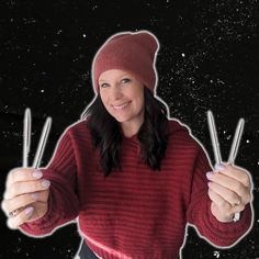 a woman in a red sweater holding two sticks