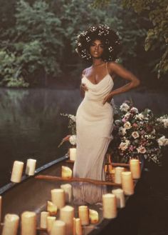 a woman in a white dress is standing on a boat with candles and flowers around her