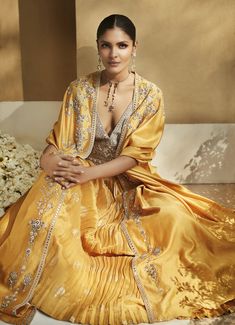 Editor's Note Indulge in vivacious elegance with this Haldi Yellow Venetian Cape Set. Crafted from silk Chanderi, it showcases luxe hand embroidery in Resham Ari, Zardozi, Sheesha, and sequins. The cape features delicate floral embroidery, while the lehenga skirt boasts handloom woven Banarasi with gathers at the waist and an embellished belt. The blouse dazzles with an inverted-V deep neckline and Sheesha work. Fabric: Silk Color: Yellow Components: Cape, skirt and blouse Disclaimer: Product co Lehenga Cape, Cape Skirt, Cape Set, Yellow Lehenga, Embellished Belt, Lehenga Skirt, Grey Blouse, Skirt And Blouse, Deep Neckline