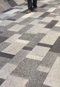 a man is standing in an airport with his luggage on the checkerboard floor