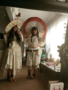 two women standing next to each other in front of a mirror with umbrellas on their heads