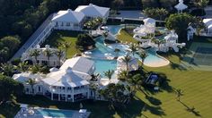 an aerial view of a large white house with a pool and tennis court in the foreground