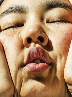 a close up of a person holding their hands to their face with her eyes closed