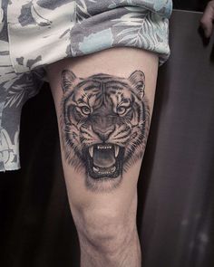 a man's leg with a tiger tattoo on it and his mouth is open