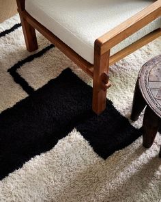 a wooden chair sitting on top of a black and white rug