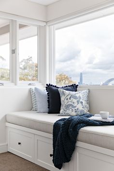 a window seat with pillows and a blanket on it