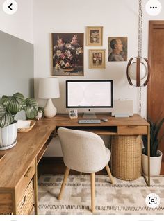 a desk with a computer on top of it next to a chair and potted plant