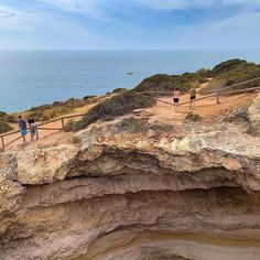 people are walking along the edge of a cliff