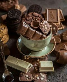 a bowl filled with chocolate and cookies next to spoons on top of a table