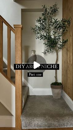 a small tree sitting in the corner of a room next to a stair case and potted plant