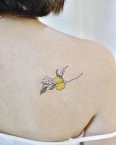 a woman with a tattoo on her back that has lemons and flowers on it