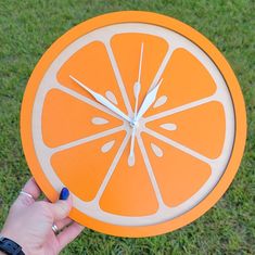 a person holding an orange clock in their hand