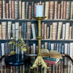 a glass topped table with books and a candle on it in front of a bookcase